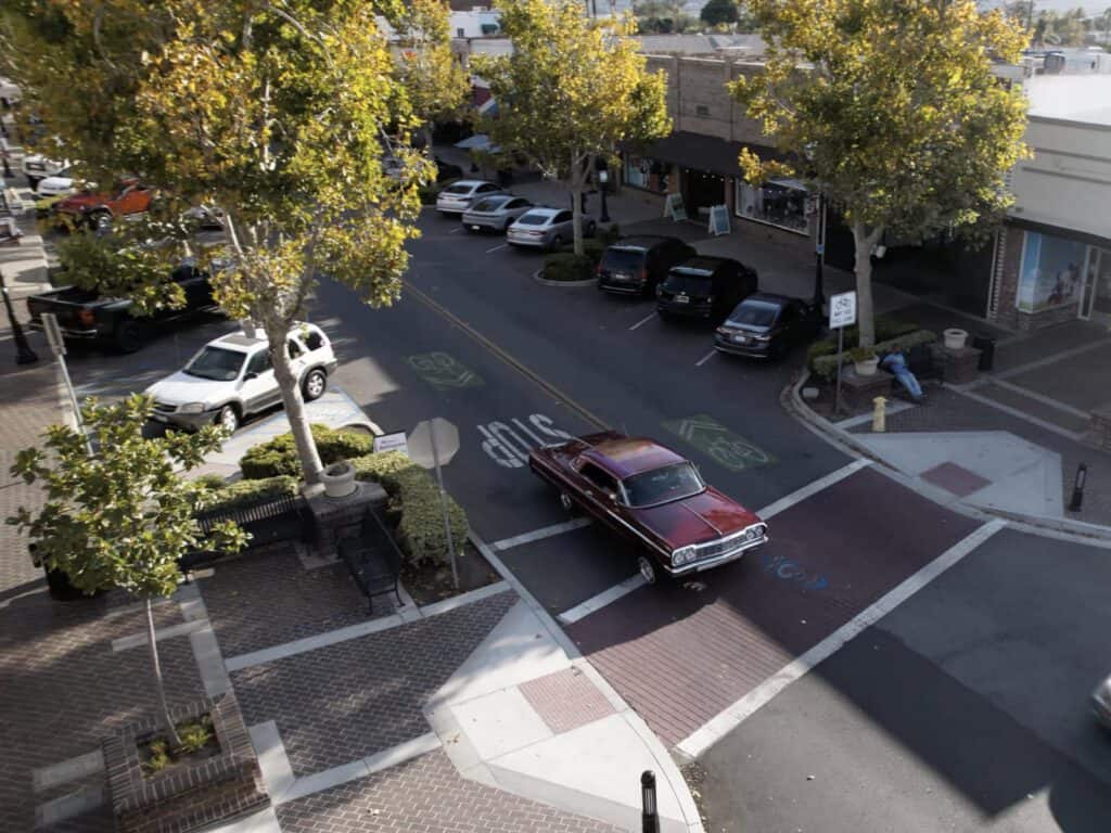 Downtown Lake Elsinore street with trees, cars, and crosswalks in sunlight.
