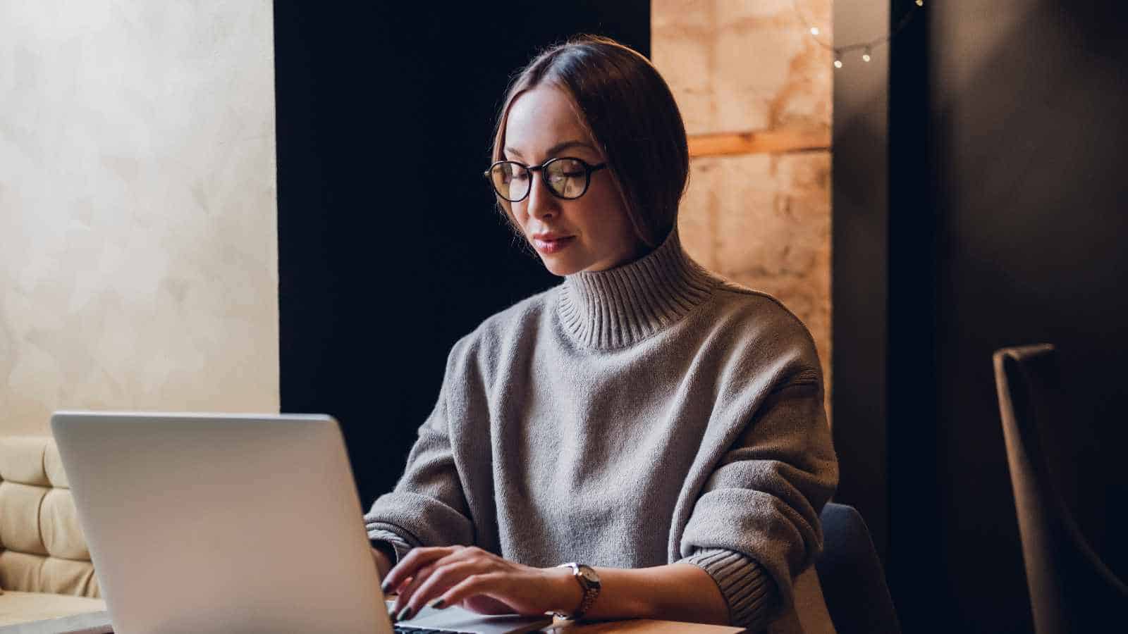 Woman working on a laptop in a cozy, modern workspace promoting sustainability.