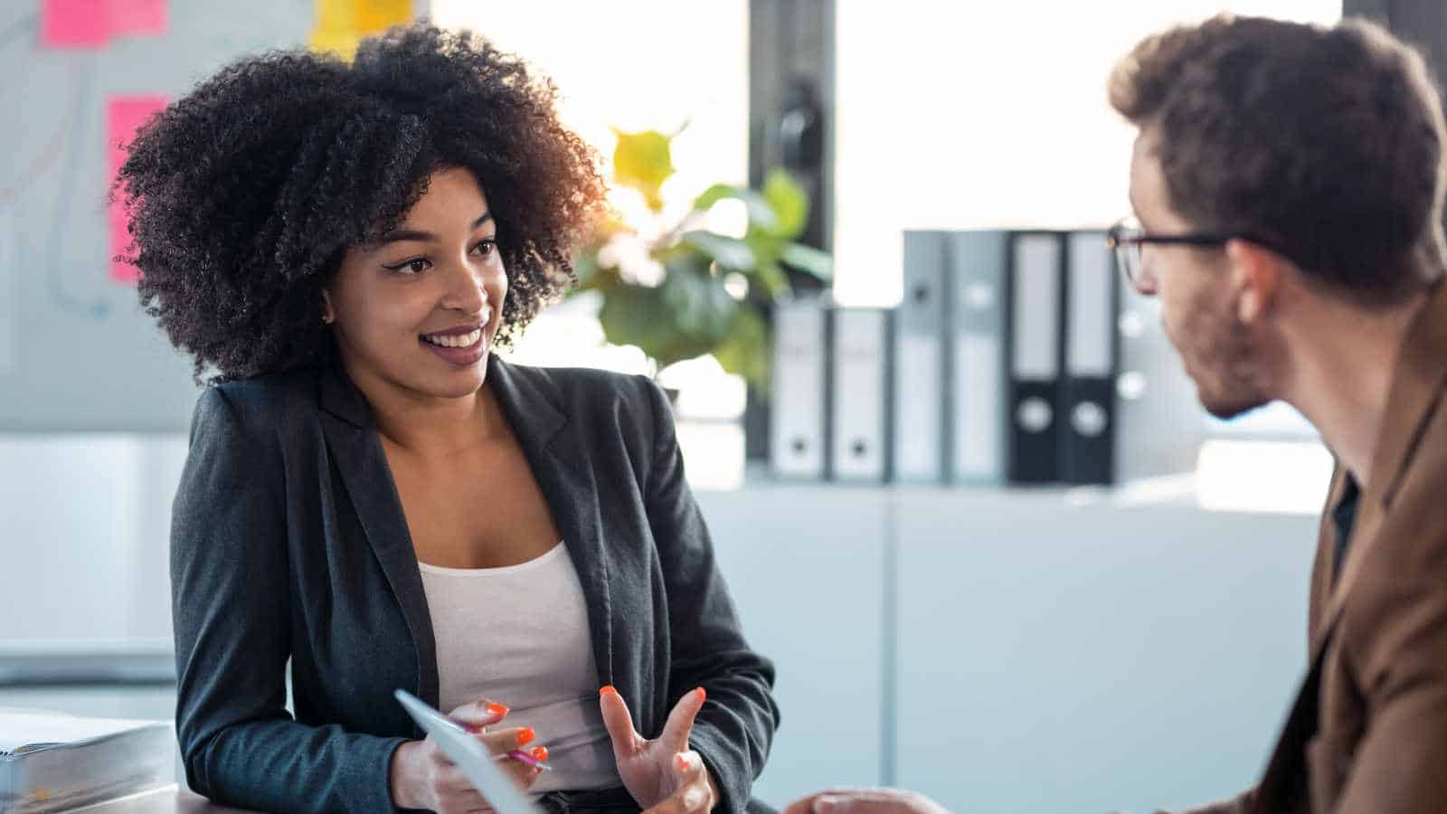 Two diverse professionals engaging in a positive discussion in a modern office setting.